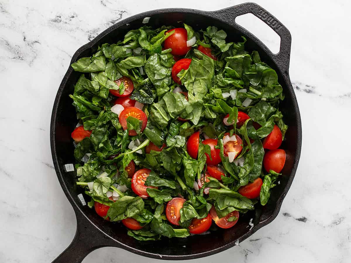 Spinach and tomatoes combined with onions in the skillet.