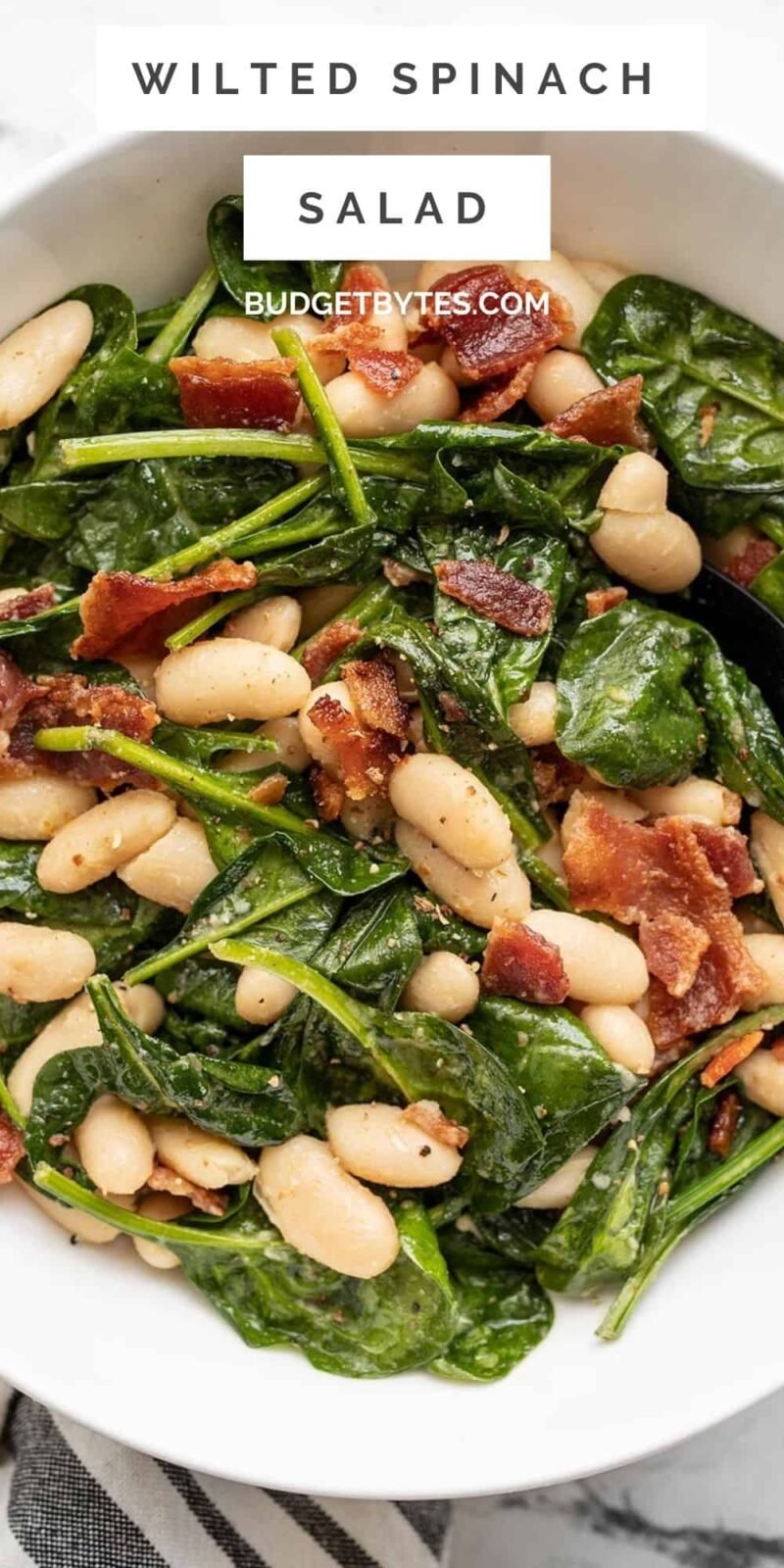 close up overhead view of a bowl full of wilted spinach salad.